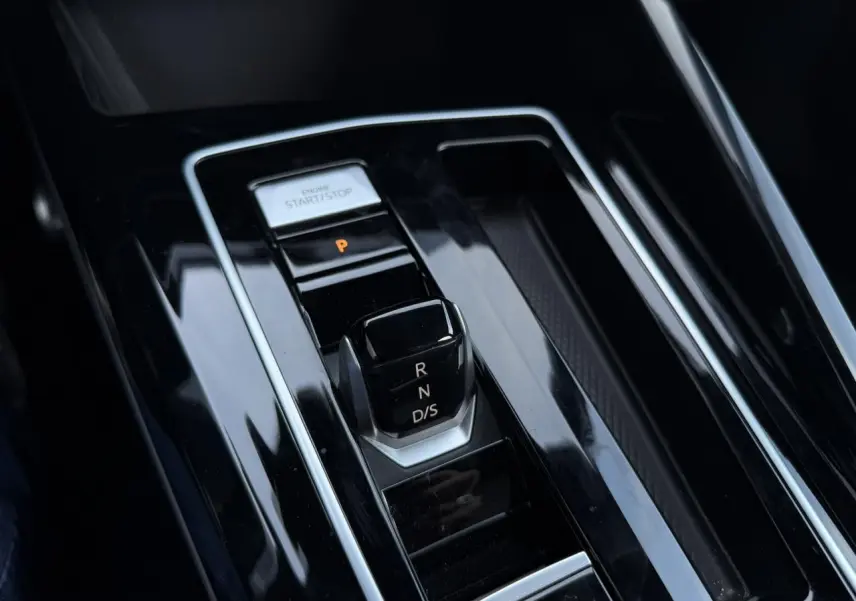 Gros plan sur la console centrale noire brillante avec sélecteur de boîte auto et bouton start/stop dans une Volkswagen Golf 8 R-Line.