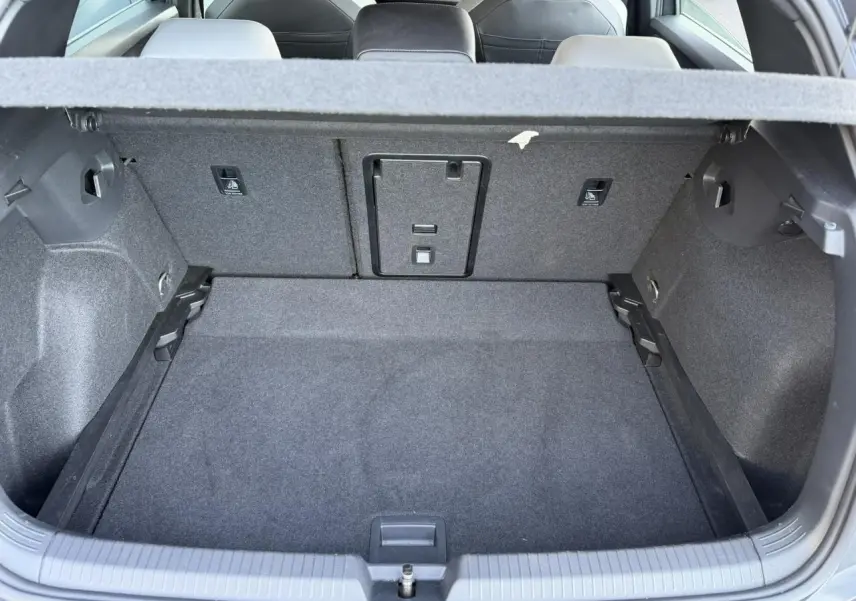 Coffre ouvert vu de l'arrière d'une Volkswagen Golf 8 Gris Urano, montrant l'espace de chargement et les sièges arrière.