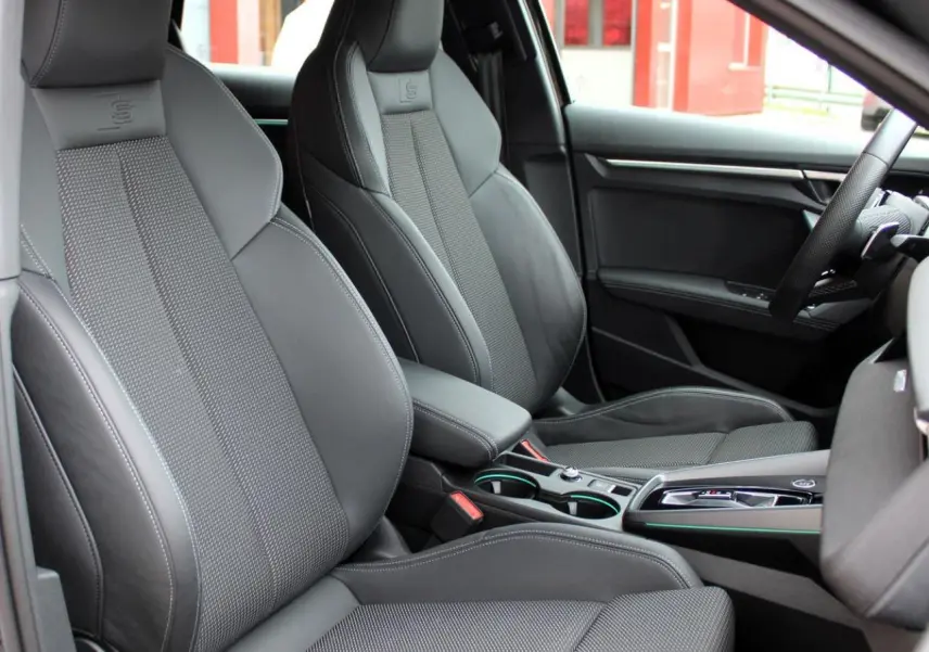 Vue intérieure côté droit des sièges sport noirs avec surpiqûres blanches et accoudoir central de l'Audi A3 Sportback 2025.