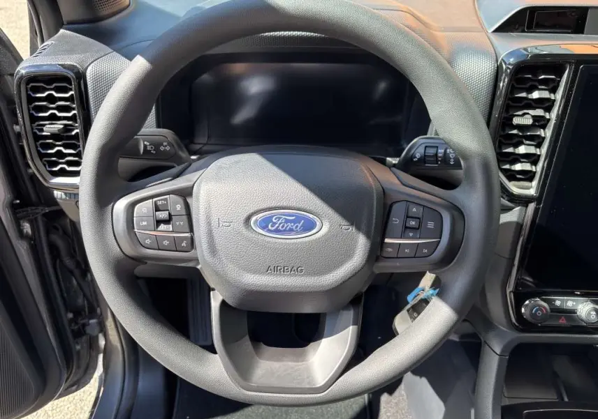 Vue rapprochée du volant cuir multifonctions gris du Ford Ranger 2026 avec tableau de bord et écran tactile visibles.