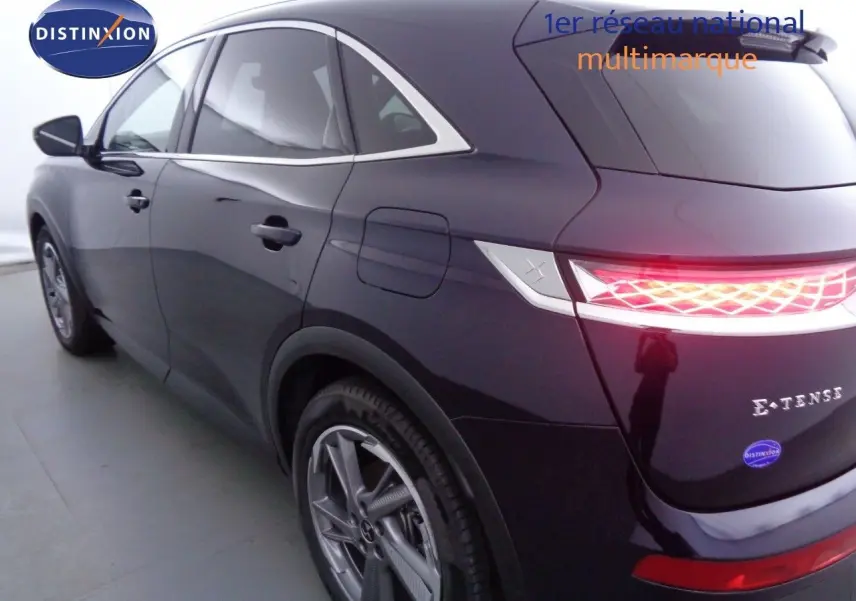 Vue 3/4 arrière droite d'un DS7 Crossback hybride rechargeable bleu encre métal avec feux arrière LED allumés.