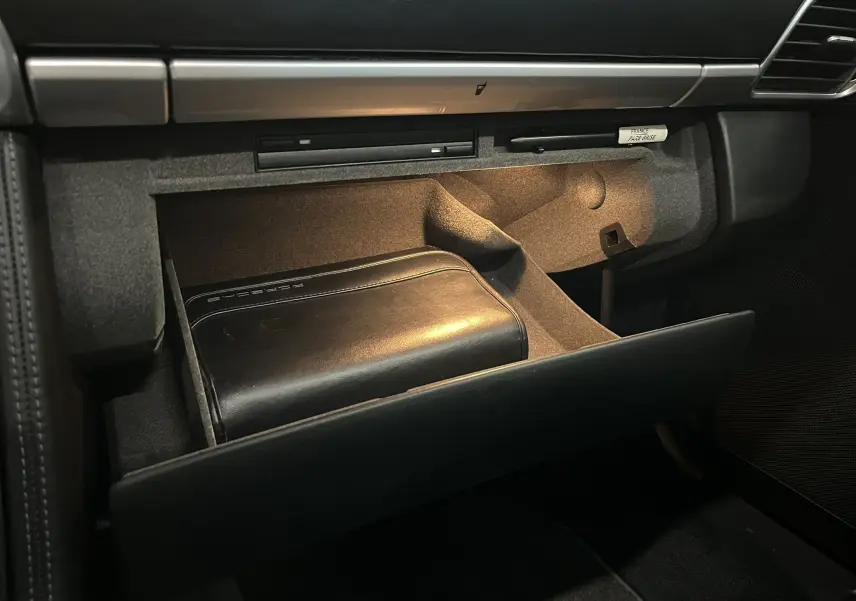 Vue intérieure sur la boîte à gants ouverte de la Porsche 911 Targa 997 Carrera 4S avec pochette cuir noire Porsche.