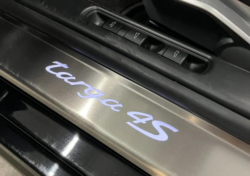 Gros plan sur le seuil de porte éclairé "targa 4S" en métal brossé, intérieur noir de la Porsche 911 Targa 997.