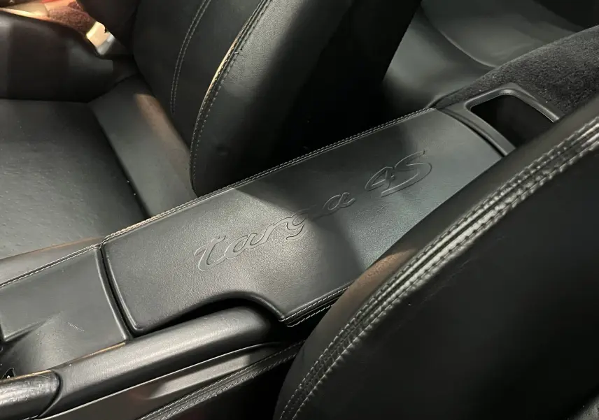 Gros plan sur l'accoudoir central en cuir noir embossé du logo "targa 4S" dans l'habitacle du Porsche 911 Targa.