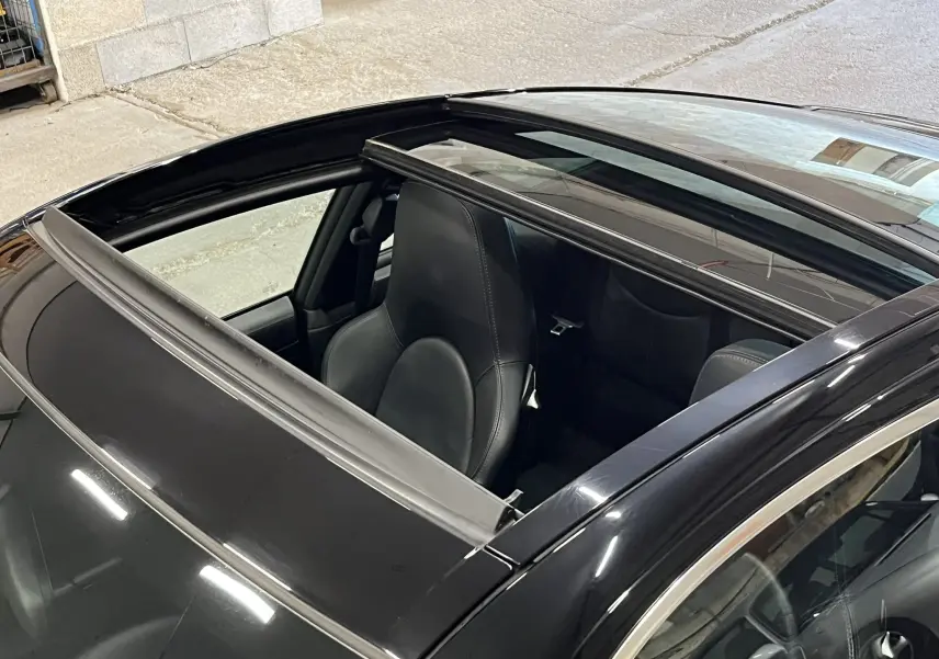 Vue rapprochée du toit ouvrant panoramique ouvert d'une Porsche 911 Targa 997 Carrera 4S noir métallisé.