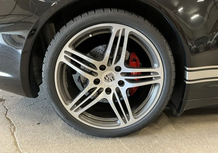 Gros plan sur la jante Turbo 19 pouces bi-ton d’une Porsche 911 Targa 997 Carrera 4S noire avec étrier de frein rouge.