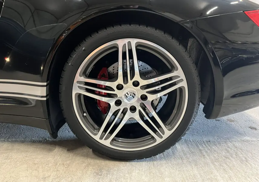 Gros plan sur la roue arrière droite noire métallisée de la Porsche 911 Targa 997 Carrera 4S avec étrier de frein rouge.