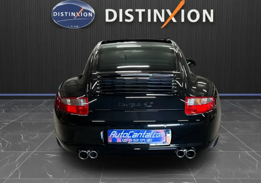 Vue arrière d'une Porsche 911 Targa 997 Carrera 4S noire métallisée avec doubles sorties d'échappement et feux rouges.