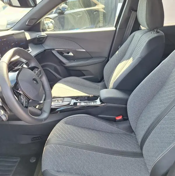 Vue intérieure côté conducteur du Peugeot 2008 Hybrid 136 e-DCS6 Allure 2025, sièges gris et tableau de bord moderne.