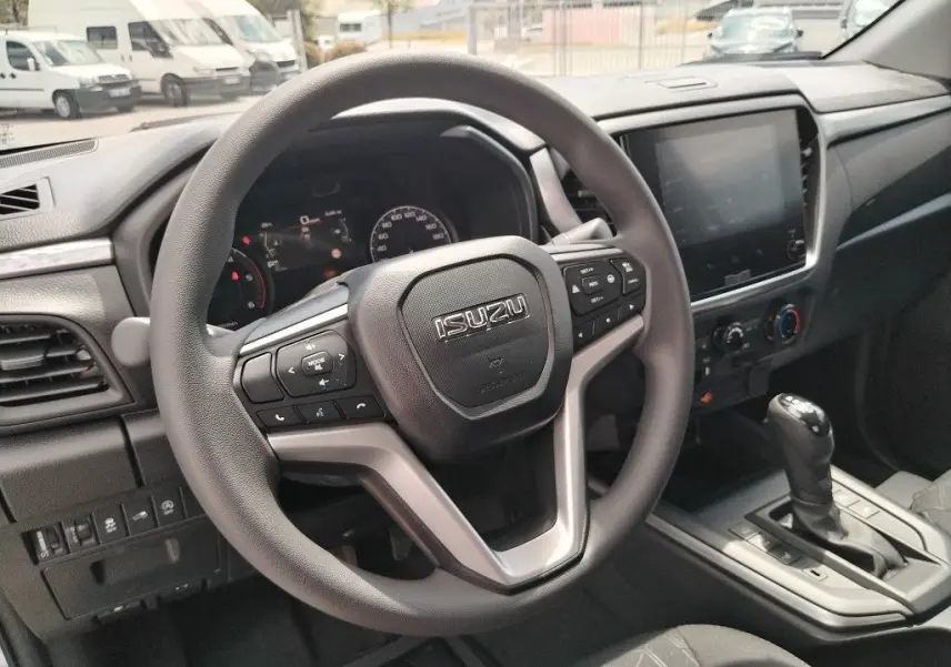 Vue intérieure centrée sur le volant multifonction d'un Isuzu D-MAX 2026 avec tableau de bord et écran tactile.