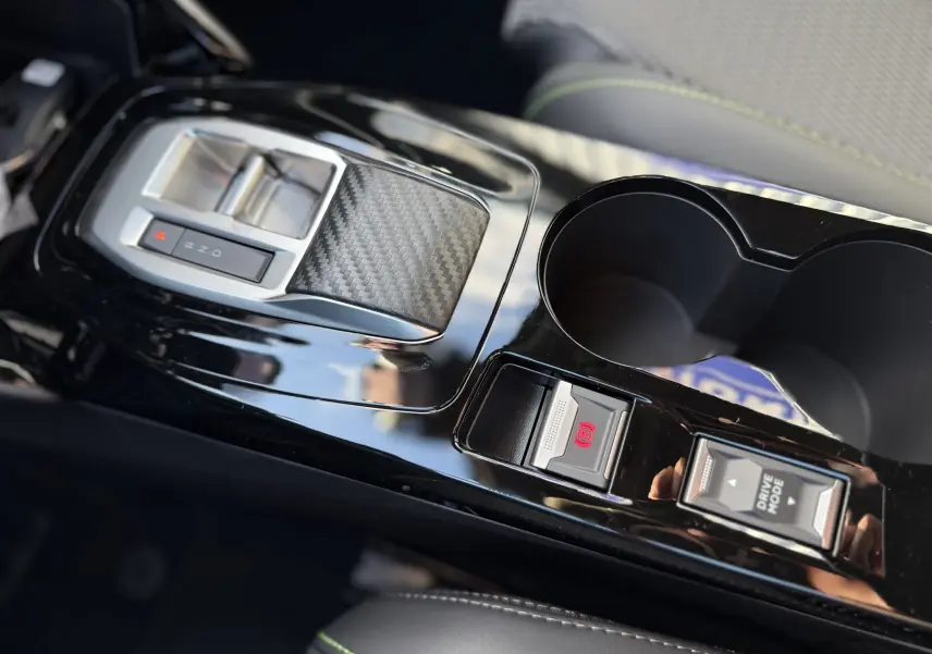 Gros plan sur la console centrale noire brillante du Peugeot 2008 Hybrid 145 GT avec levier de vitesses et commandes Drive Mode.