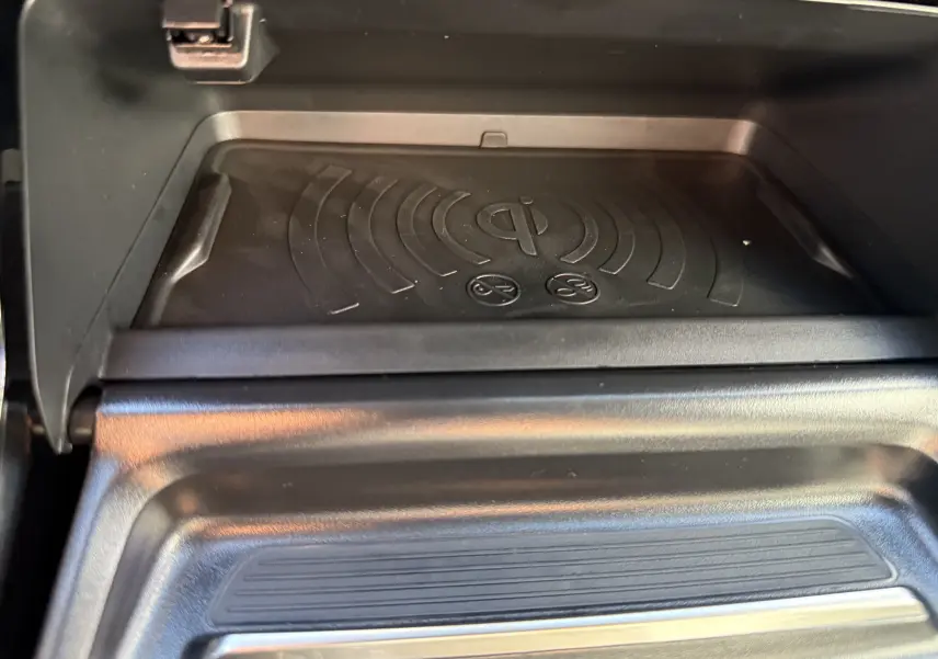 Gros plan sur le chargeur à induction noir intégré dans la console centrale du Peugeot 2008 Hybrid 145 GT.