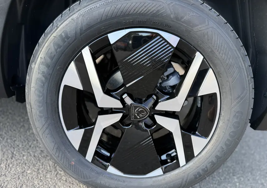 Gros plan sur la jante noire et argentée du Peugeot 2008 Hybrid 145 gris Artense, mettant en valeur le logo lion central.