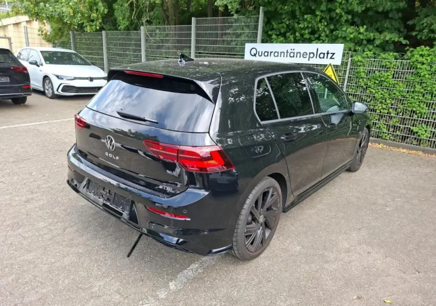 Vue 3/4 arrière droite d'une Volkswagen Golf 8 noire avec jantes alliage noires et vitres teintées.