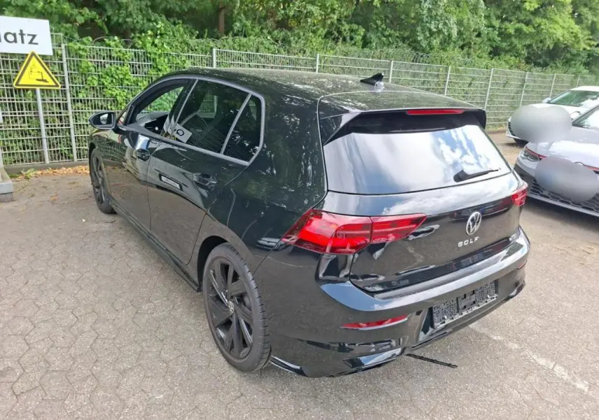 Volkswagen Golf 8 R-Line noire vue 3/4 arrière droit, avec jantes noires et feux arrière LED défilants.