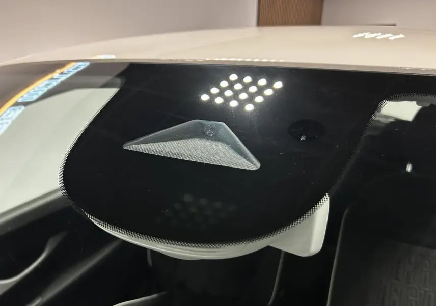 Détail du capteur d'alerte de franchissement de ligne visible derrière le pare-brise d'une Fiat 500 blanche électrique.