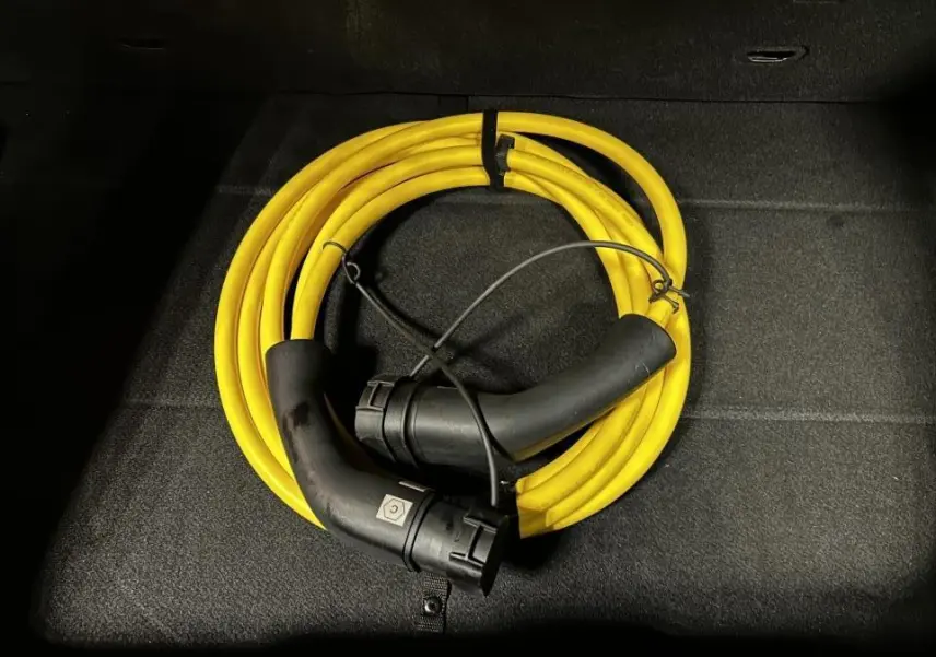 Câble de recharge jaune enroulé dans le coffre d'une FIAT 500 électrique blanche 2024.