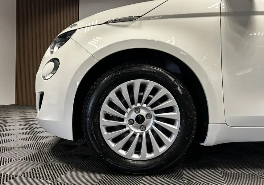 Gros plan sur la roue avant gauche et partie avant blanche d'une FIAT 500 électrique 2024 avec jante acier 15 pouces.