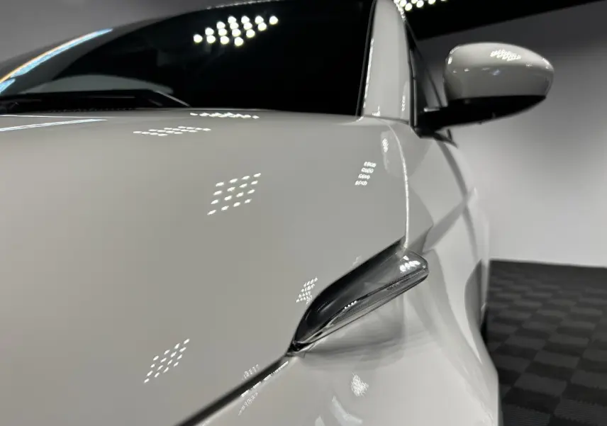 Gros plan sur le rétroviseur droit blanc d'une Fiat 500 électrique 2024 avec carrosserie lisse et reflets lumineux.