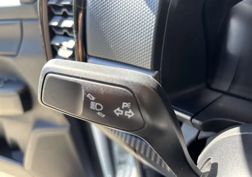 Gros plan sur la manette de clignotants noire à gauche du volant dans l’habitacle du Ford Ranger blanc glacier.