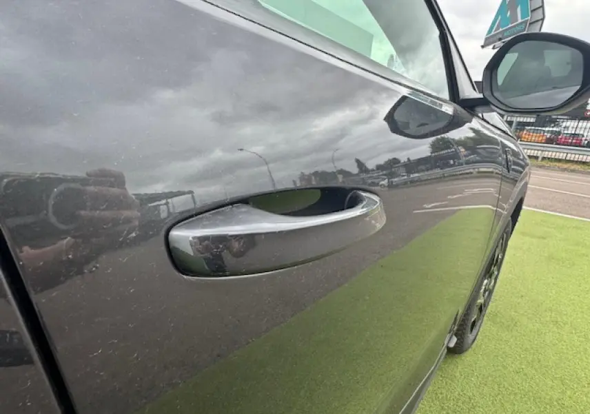 Poignée de porte côté gauche d’un Peugeot 3008 gris titane avec toit noir, vue rapprochée en extérieur.