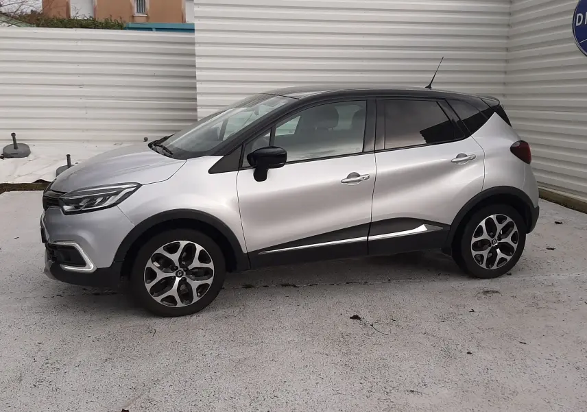 Vue de profil droit du Renault Captur gris avec toit noir, soulignant ses jantes alliage et ses lignes modernes.