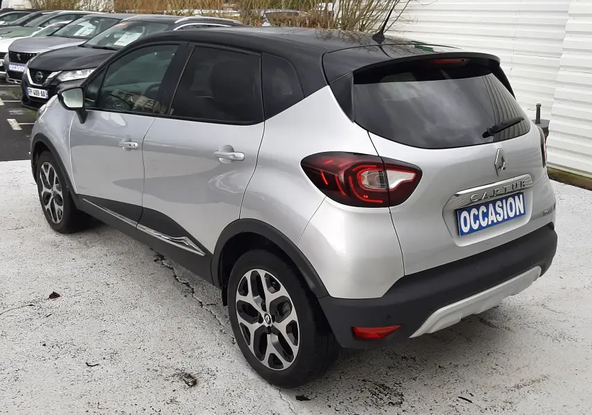Vue 3/4 arrière droite d'un Renault Captur gris à toit noir avec jantes alliage et vitres teintées.