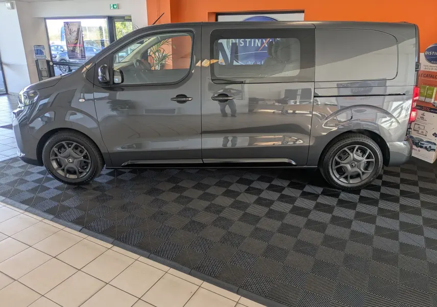 Vue de profil côté gauche d'un Citroën Jumpy Cabine Approfondie gris titane en showroom avec jantes noires.