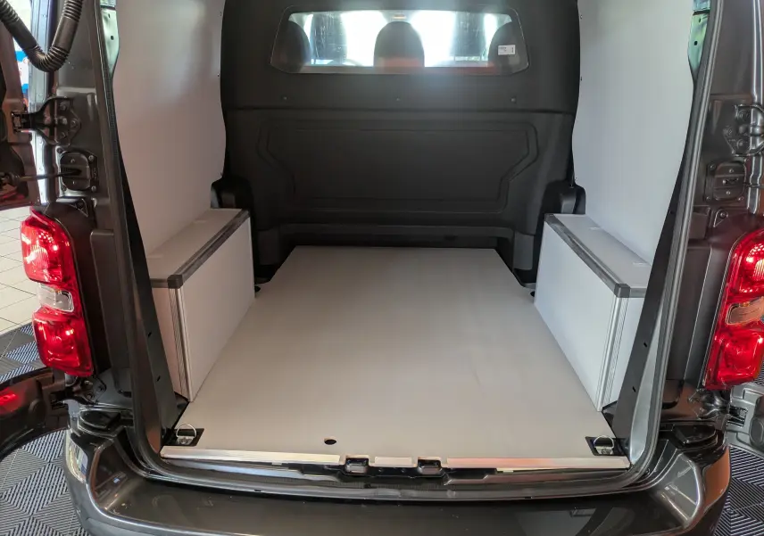 Vue arrière du Citroën Jumpy gris titane montrant l’espace de chargement avec plancher et coffrages bois blancs.