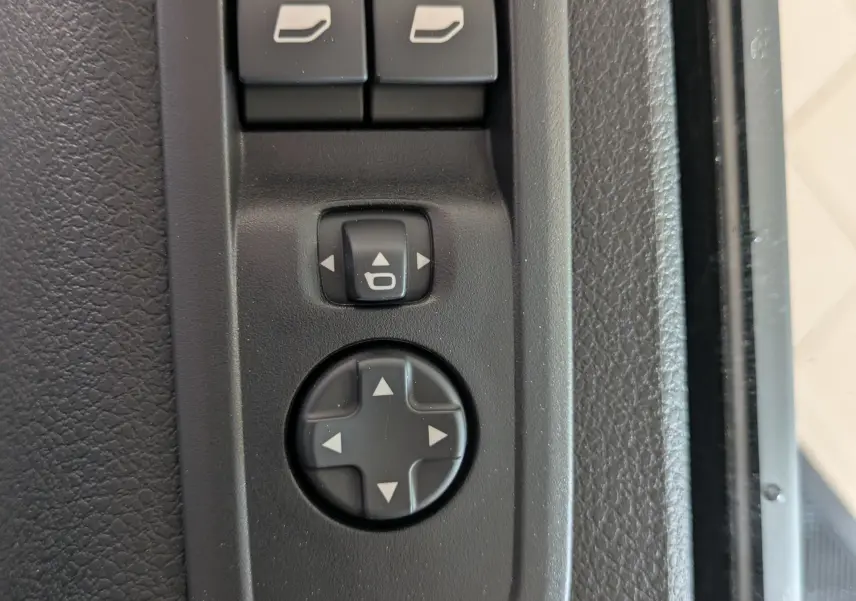 Gros plan sur les commandes de réglage des rétroviseurs et vitres électriques côté conducteur du Citroën Jumpy gris titane.