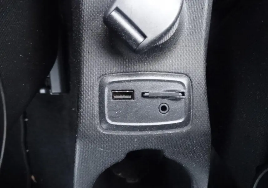 Gros plan sur les prises USB et auxiliaire intégrées dans la console centrale noire d'une Smart Forfour électrique blanche.