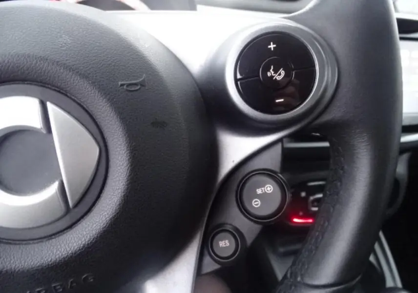 Gros plan sur le volant cuir multifonctions de la Smart Forfour Electric Drive Prime 2018 avec commandes de régulateur de vitesse.