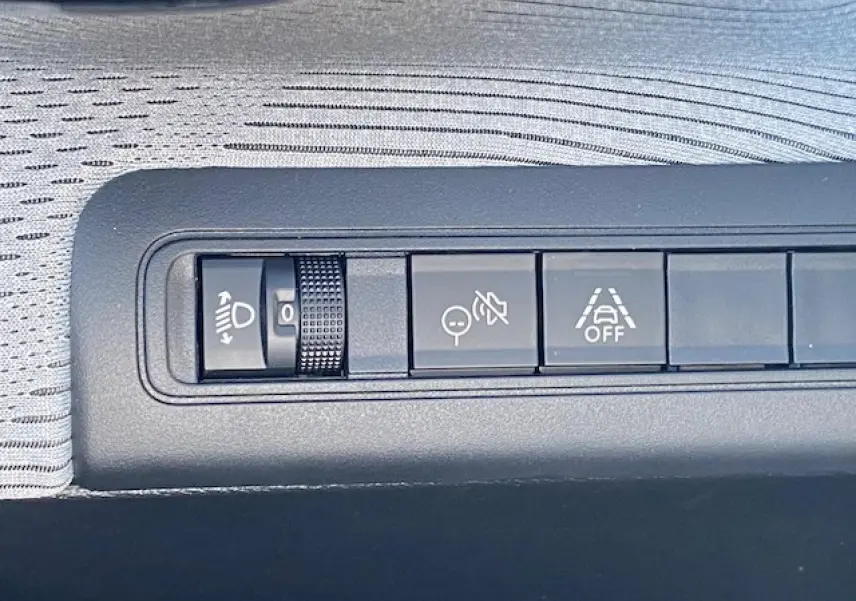 Gros plan sur les boutons de réglage d’éclairage et d’aides à la conduite dans l’habitacle gris clair du Citroën C3 Aircross.