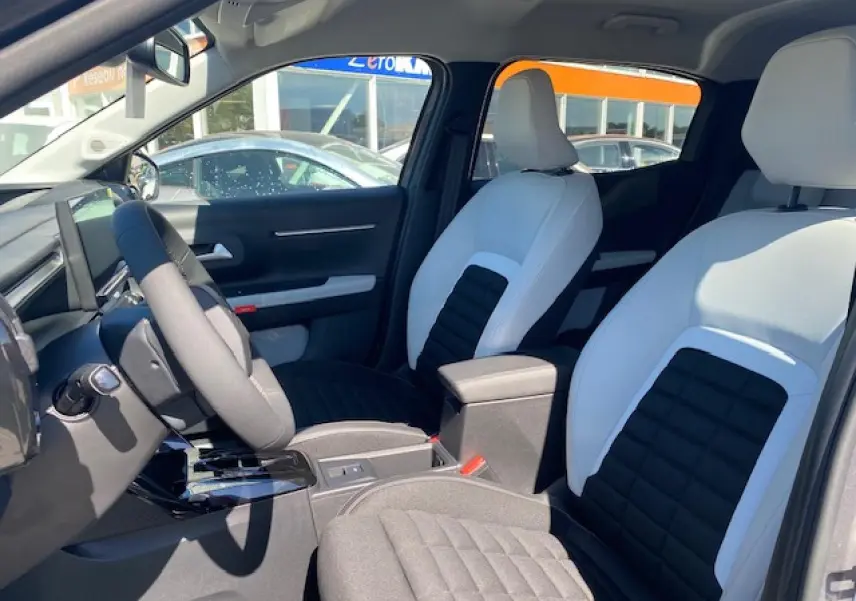 Vue intérieure avant du Citroën C3 Aircross 2026, sièges bicolores noir et blanc avec console centrale et volant multifonctions.