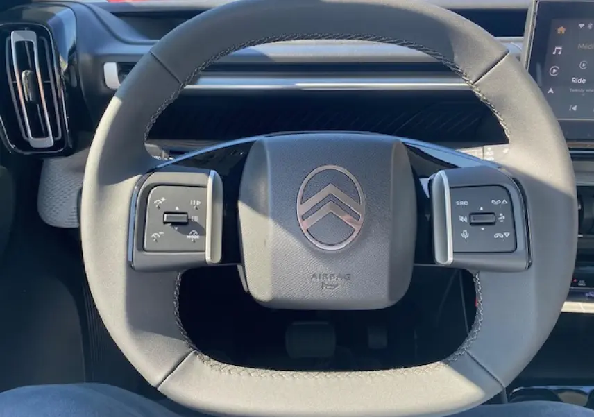 Gros plan sur le volant multifonctions gris du Citroën C3 Aircross 2026 avec logo chevrons et commandes intégrées.