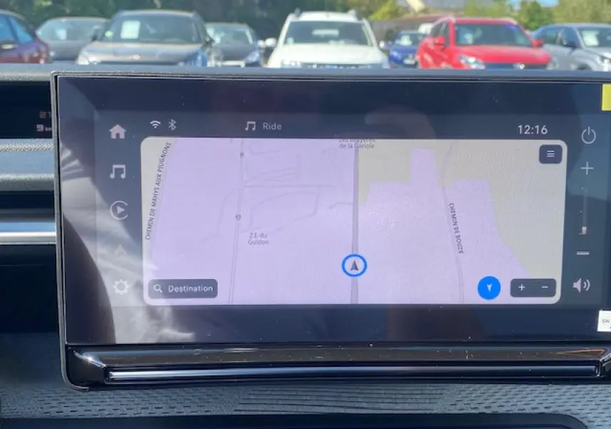 Vue intérieure centrée sur l'écran tactile de navigation du Citroën C3 Aircross 2026, avec tableau de bord gris et environnement extérieur flou.