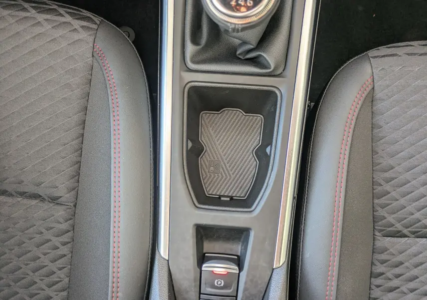Vue plongeante sur la console centrale de la Renault Clio VI TCe 115ch, boîte manuelle, sièges noirs avec surpiqûres rouges.