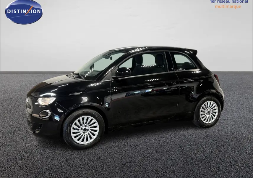 Profil droit de la Fiat 500 électrique noire 2024 avec jantes acier 15 pouces dans un showroom lumineux.