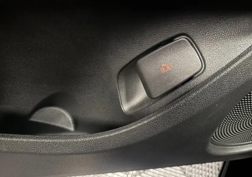 Gros plan sur le bouton de verrouillage des portes côté intérieur d’une FIAT 500 électrique noire 2024.