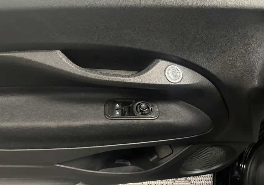 Intérieur côté gauche de la porte d’une Fiat 500 électrique noire 2024, avec commandes de vitres et haut-parleur intégré.