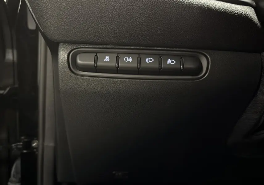 Gros plan sur les commandes de réglage des phares et aides à la conduite dans une Fiat 500 électrique noire 2024.