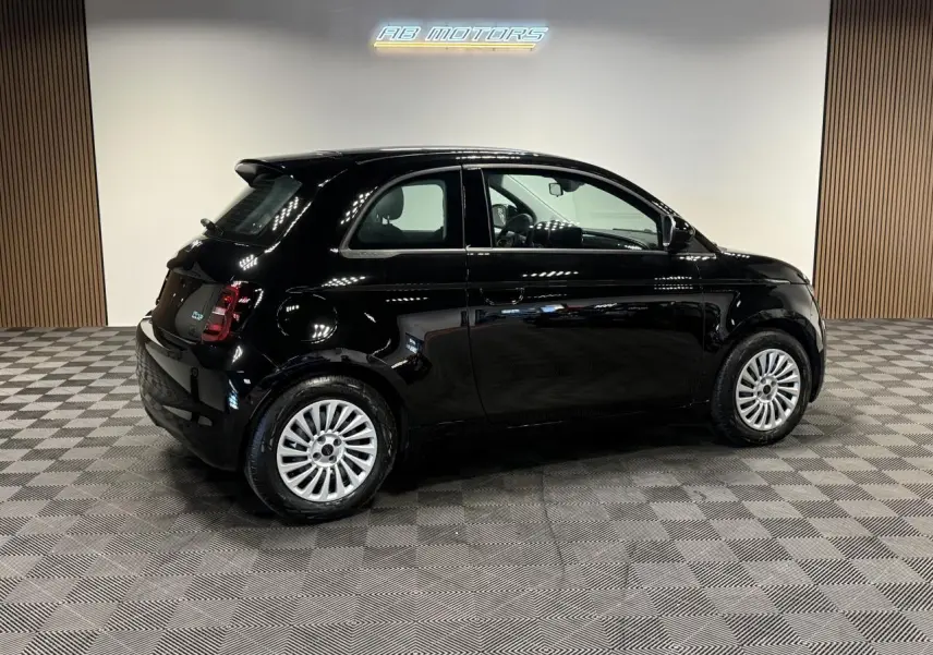 Profil droit d'une Fiat 500 électrique noire 2024, avec jantes acier 15 pouces et éclairage LED arrière visible.