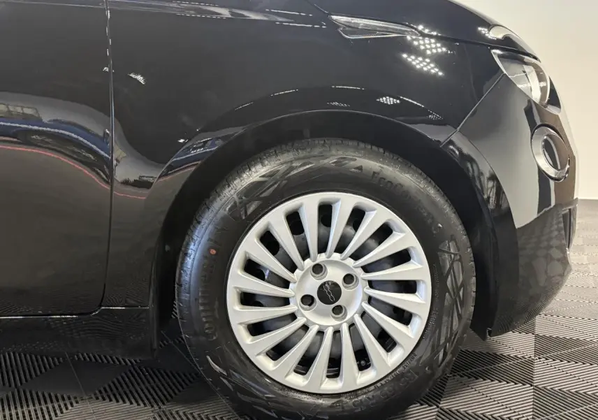 Gros plan sur la roue avant droite d'une FIAT 500 noire 2024 avec jante acier 15 pouces et logo central.