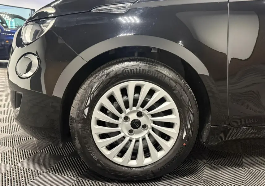 Gros plan sur la roue avant gauche noire d’une Fiat 500 électrique 2024 avec jante acier 15 pouces.