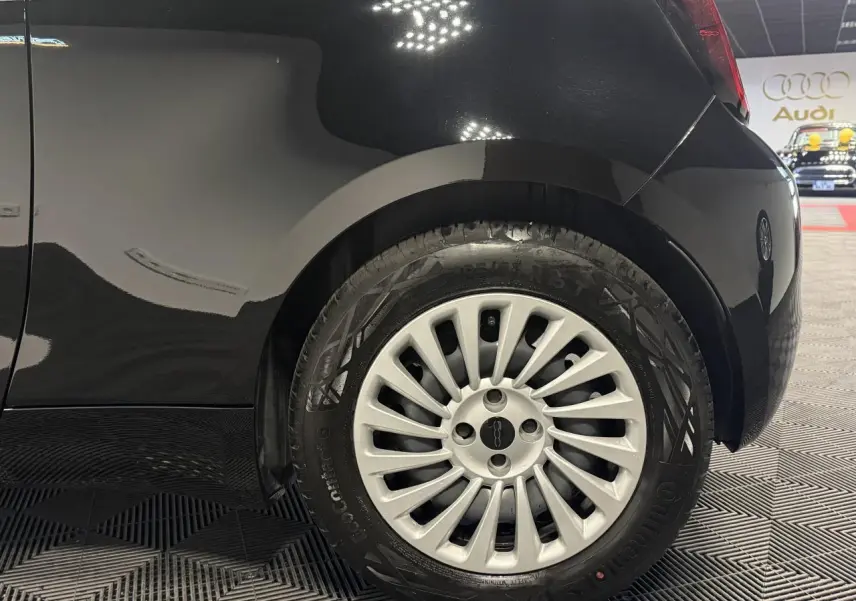 Gros plan sur la roue arrière droite d’une FIAT 500 électrique noire avec jante acier 15 pouces et logo central.