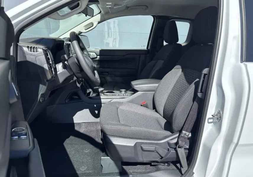 Vue intérieure côté conducteur du Ford Ranger blanc glacier 2026, sièges tissu gris et tableau de bord noir.