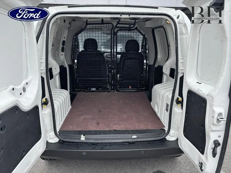 Vue arrière intérieure du FIAT Fiorino blanc 2018 avec cloison modulable et double portes ouvertes sur le compartiment de chargement.