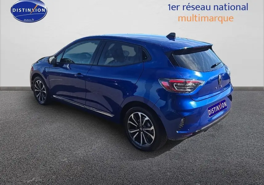 Renault Clio V bleu iron vue 3/4 arrière droit, avec jantes alu et becquet arrière noir brillant.