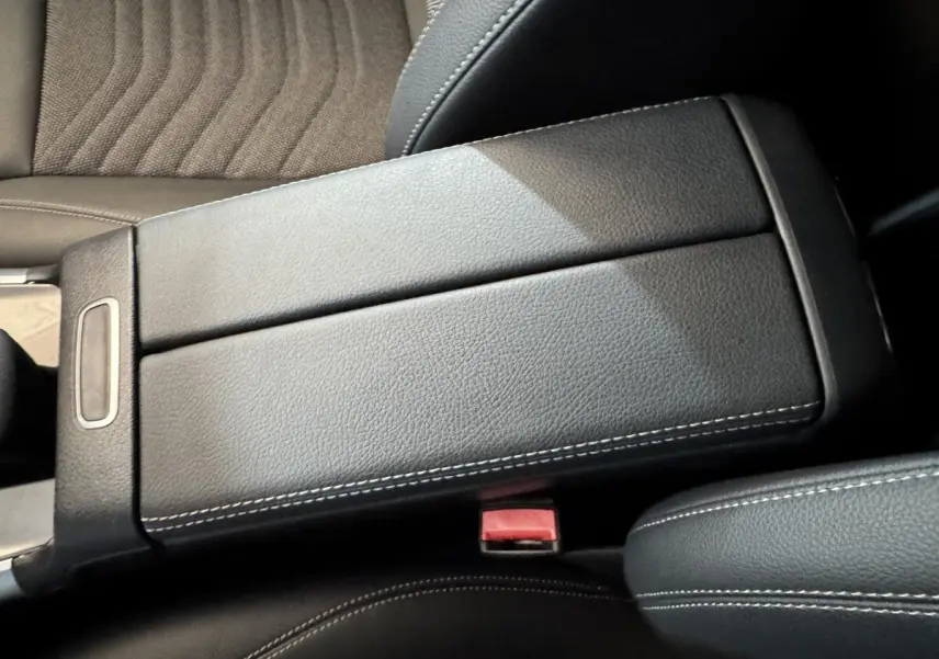 Vue rapprochée de l'accoudoir central en cuir noir avec surpiqûres blanches dans l'habitacle du Mercedes GLA 250 e gris foncé.