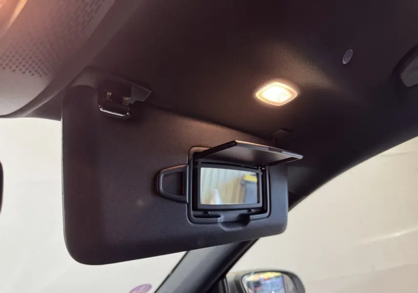 Vue intérieure rapprochée du pare-soleil côté conducteur avec miroir éclairé dans un Mercedes GLA 250 e gris foncé 2023.
